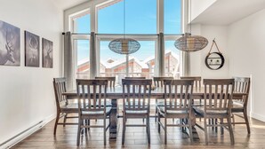 A dining area with a large window, wooden chairs, and a round table. - Compfortable Chalet to Rent at Stoneham located at the Mountain (CITQ: 287663) (Stoneham-et-Tewkesbury)