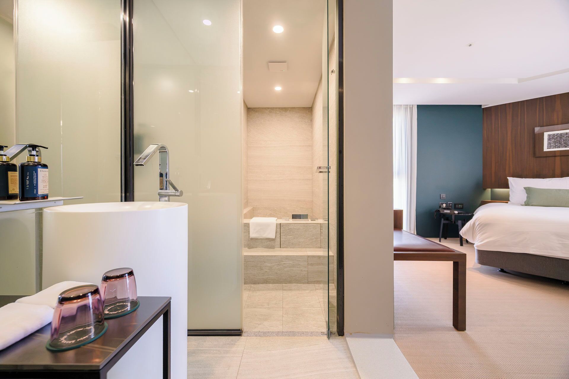 A hotel room with a bed, bedside table, and a bathroom with a shower and sink.