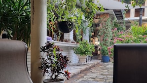Eine Terrasse mit Steinboden, einem Stuhl und Topfpflanzen.