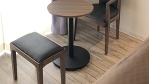 Una habitación pequeña con una mesa redonda de madera y dos sillas, una con asiento acolchado.