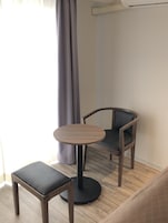 Una habitación pequeña con una mesa redonda de madera y dos sillas, una con asiento acolchado.