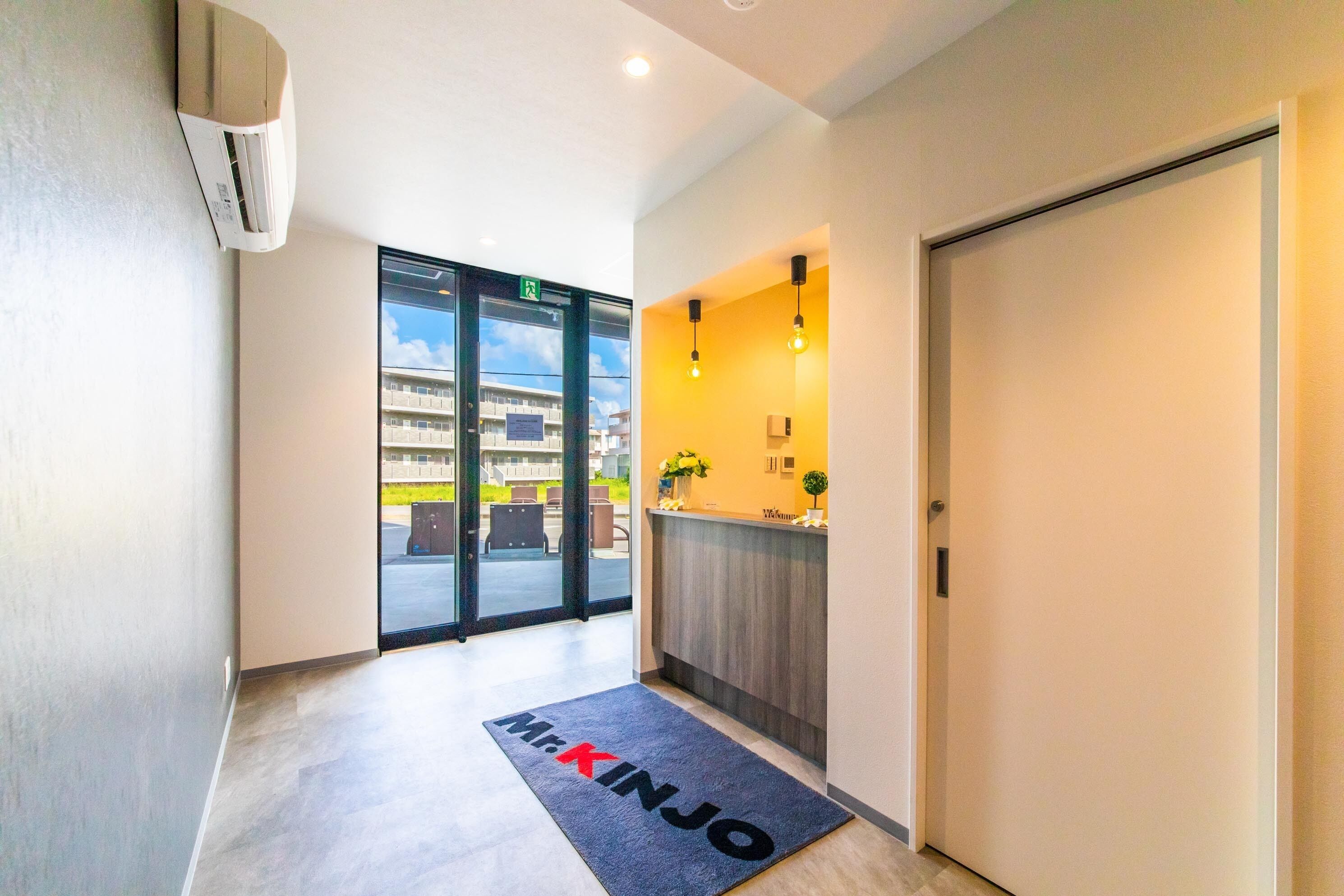 A hotel reception area with a modern design, including a reception desk, a welcome mat, and a view of the outside.