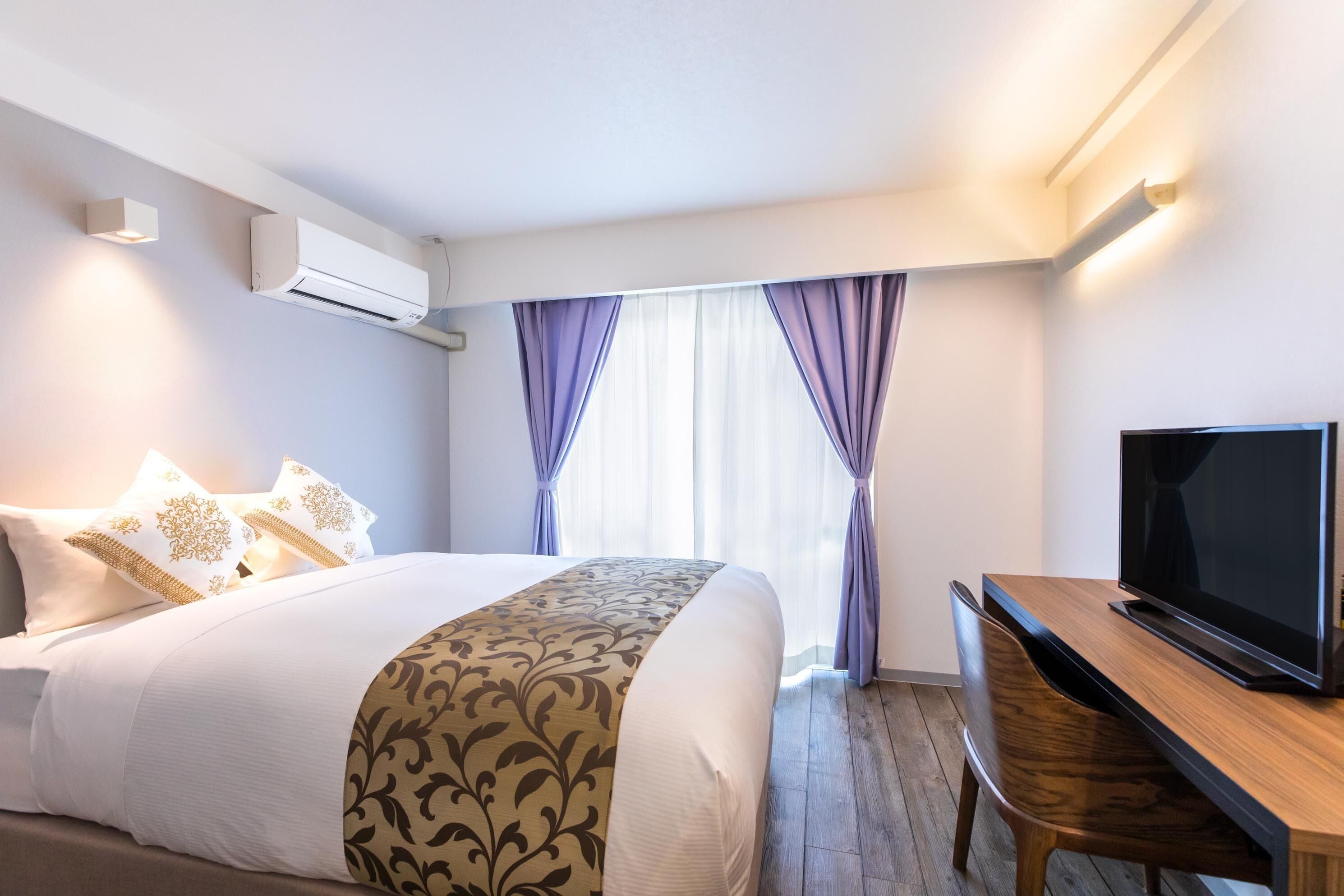 Una camera d'albergo con un letto, una televisione e una scrivania.