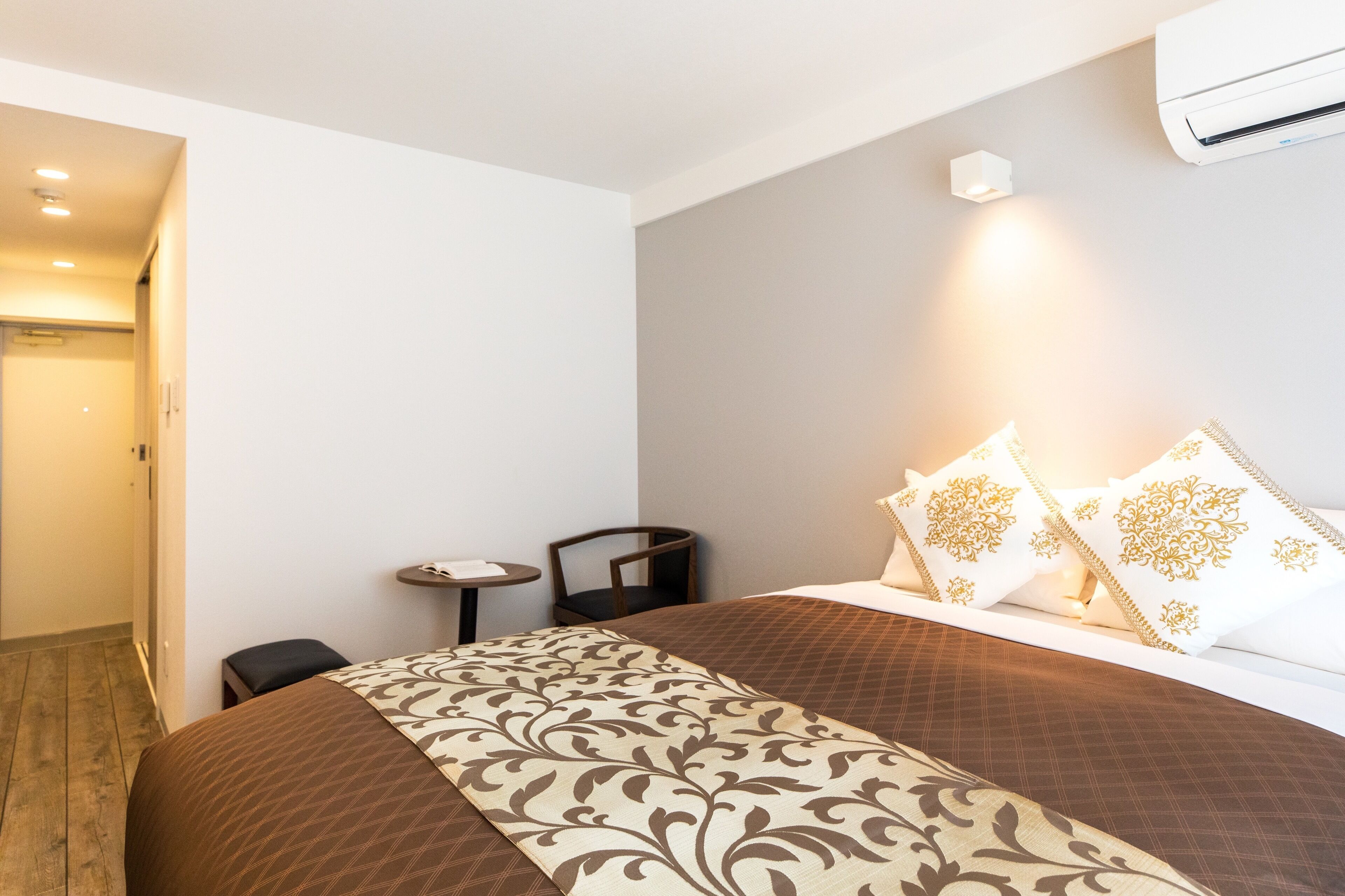 Une chambre d’hôtel équipée d’un lit, d’une petite table, d’une chaise et d’un appareil de climatisation.