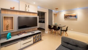 A modern living room with a large flat-screen TV, a dining area with a glass table and chairs, and a sofa. - Welcome Rio - Ipanema Beach - Posto 9 (Rio de Janeiro)