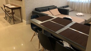A modern living room with a sofa, a dining table with chairs, and a small desk with a chair. - Welcome Rio - Ipanema Beach - Posto 9 (Rio de Janeiro)