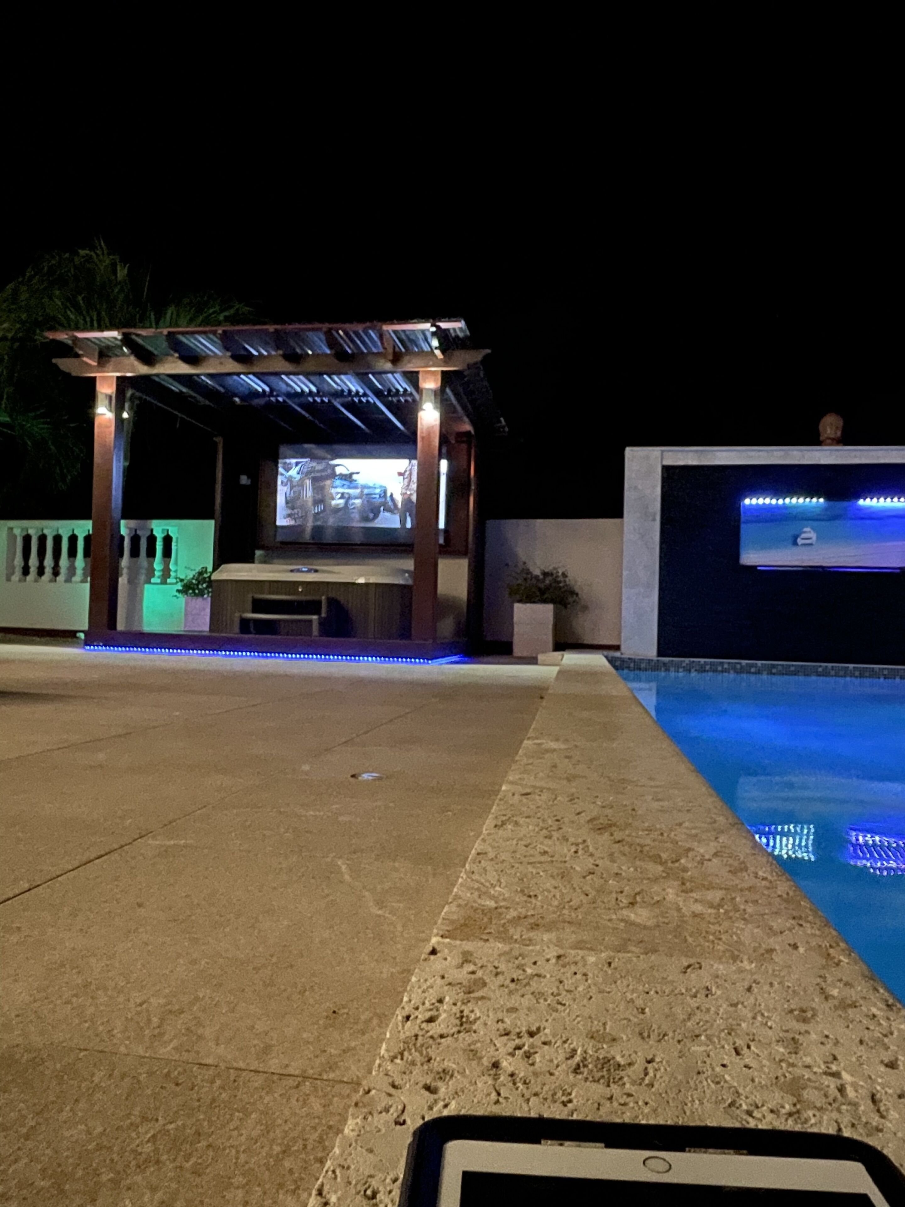 Et poolområde med et pergola og et tv-skærm.