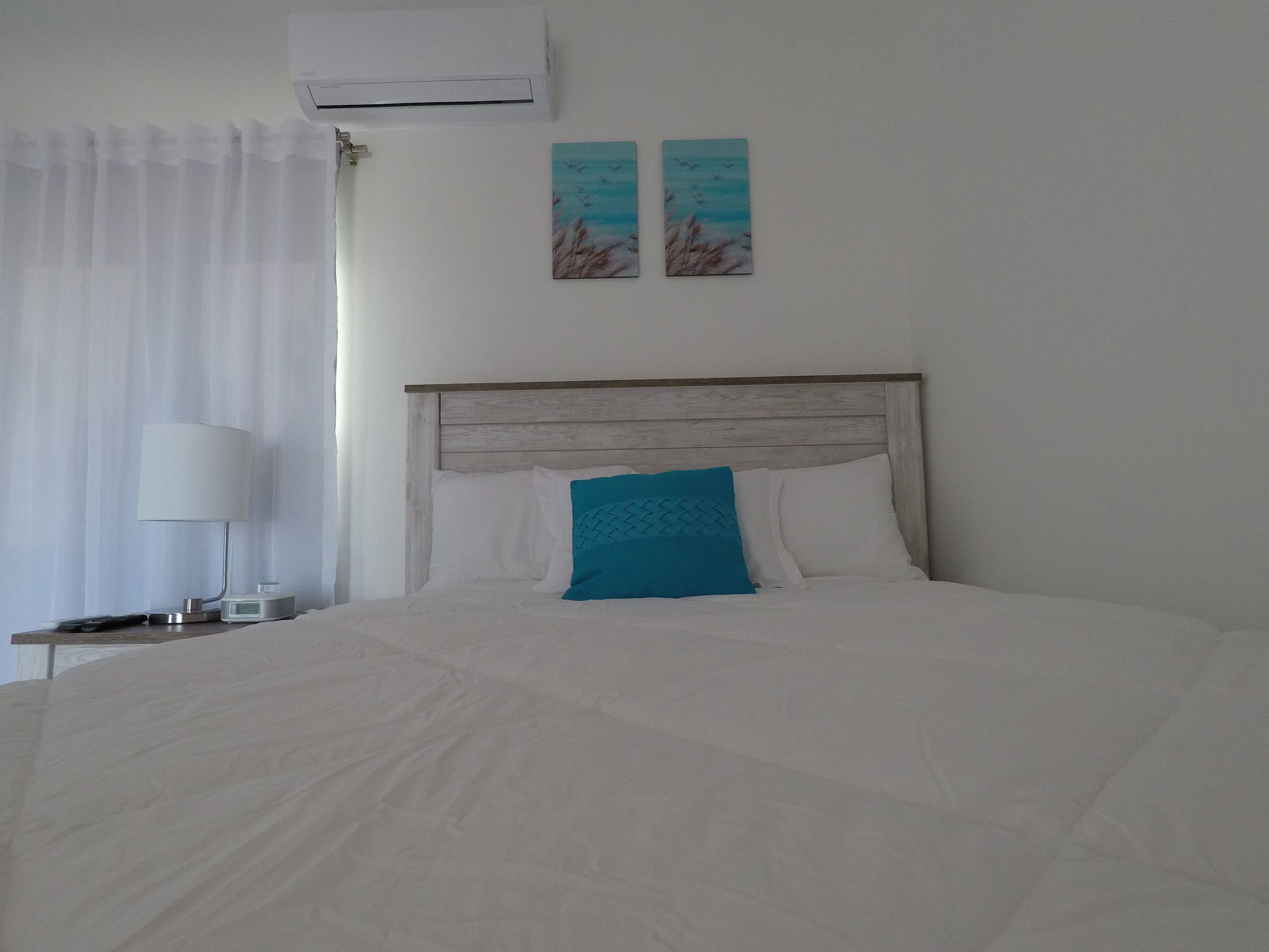 Habitación de hotel con una cama grande, una mesita de noche con lámpara y dos obras de arte en la pared.