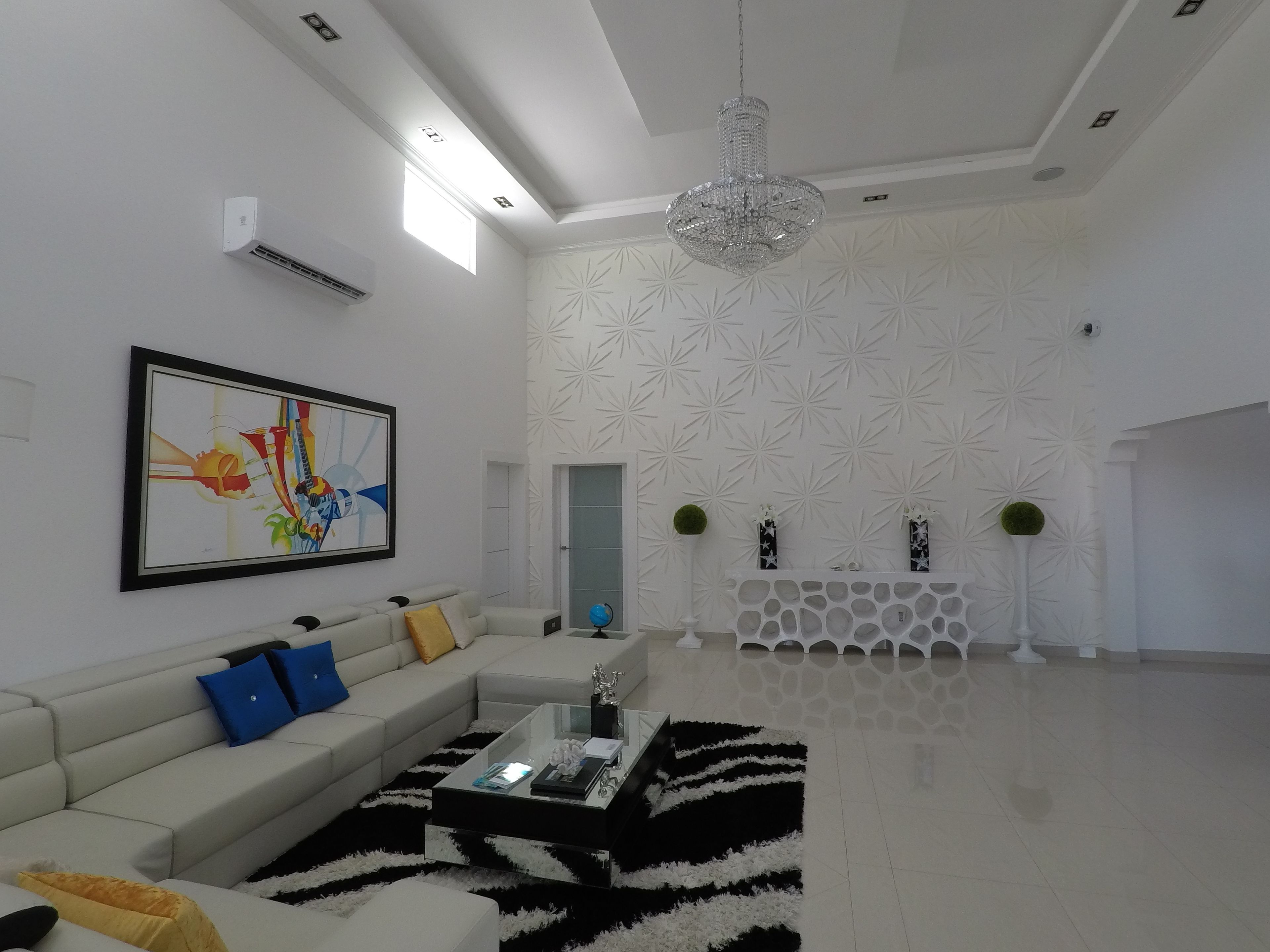 A modern living room with a sectional sofa, a glass coffee table, and a chandelier.