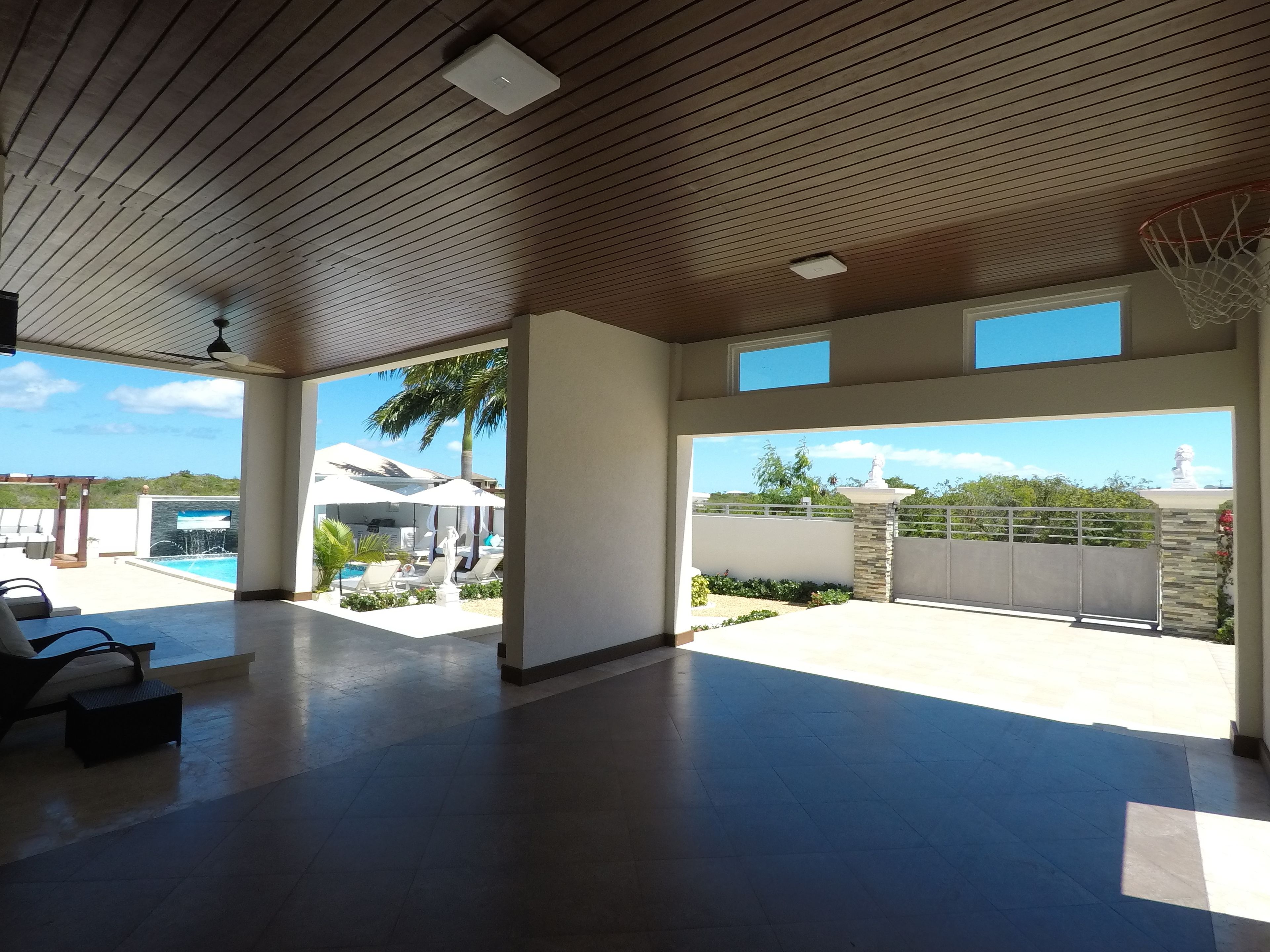 A spacious indoor area with a pool, lounge chairs, and a basketball hoop.