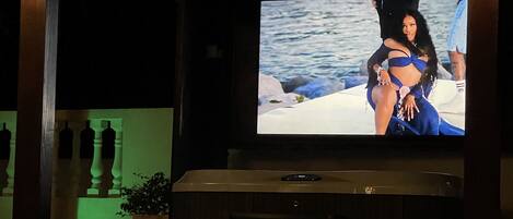 A darkened room with a large screen displaying a person on a boat.