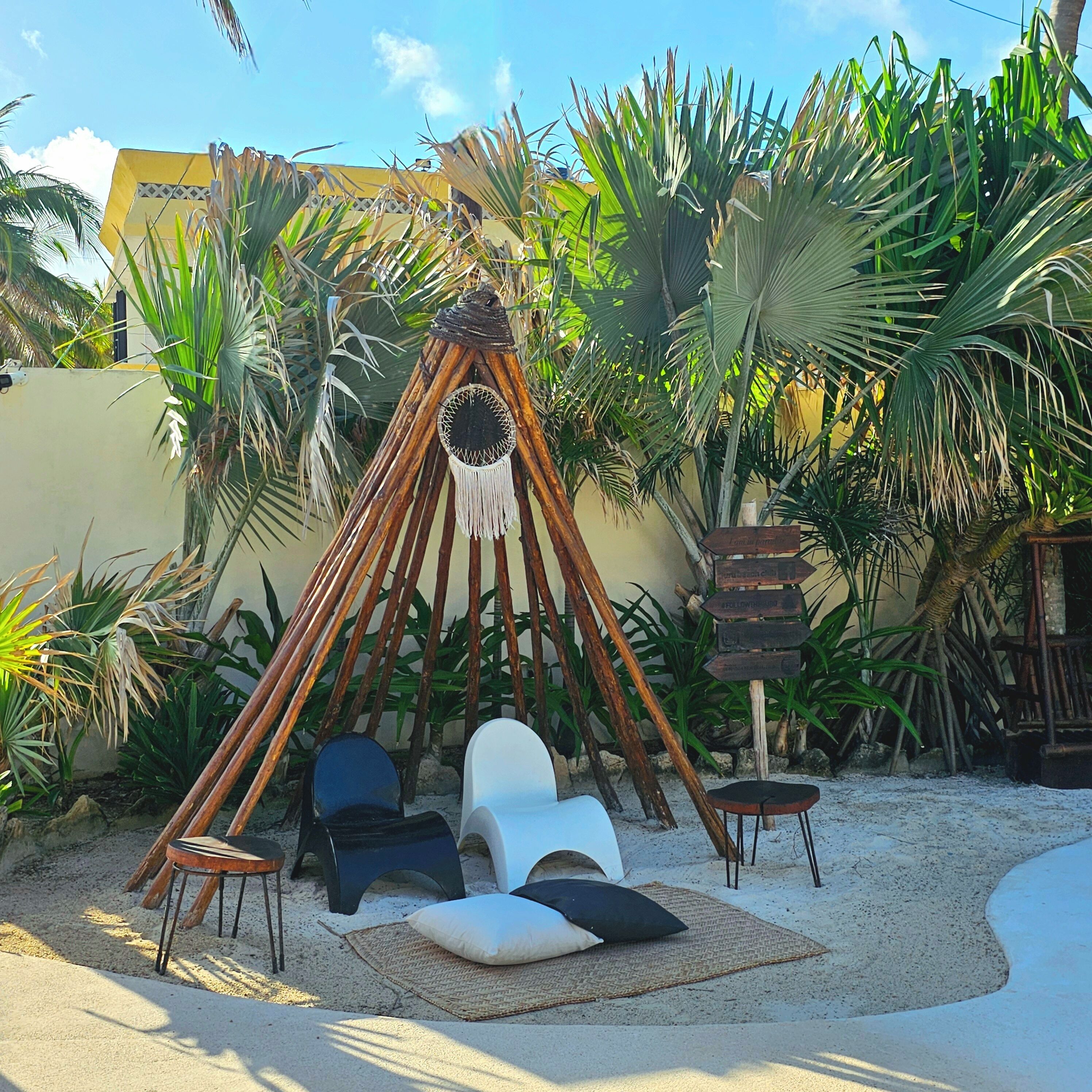 A hammock chair set up in a tropical garden with a palm tree backdrop.