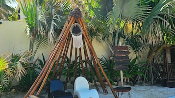 A hammock chair set up in a tropical garden with a palm tree backdrop.