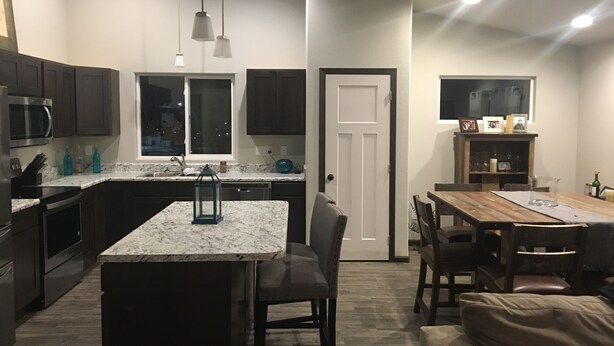 A modern kitchen with dark cabinets, a marble countertop, and pendant lighting. - Perfect get away that is minutes from Legendary Downtown Sturgis! (Sturgis)