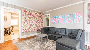 A modern living room with a grey leather sofa, a grey coffee table, and a floral wall decoration. - Insta Worthy Stay! - Fun in Downtown Raleigh! (Raleigh)