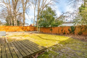 Enjoy the serene atmosphere of this backyard with a wooden deck and lush surroundings.