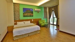 A hotel room with a large bed, a green sofa, a small table, and a painting on the wall. - Chang Cheng Min Su (Magong)