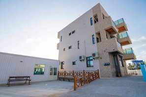 A multi-story building with a flat facade, several balconies, and a gated entrance.