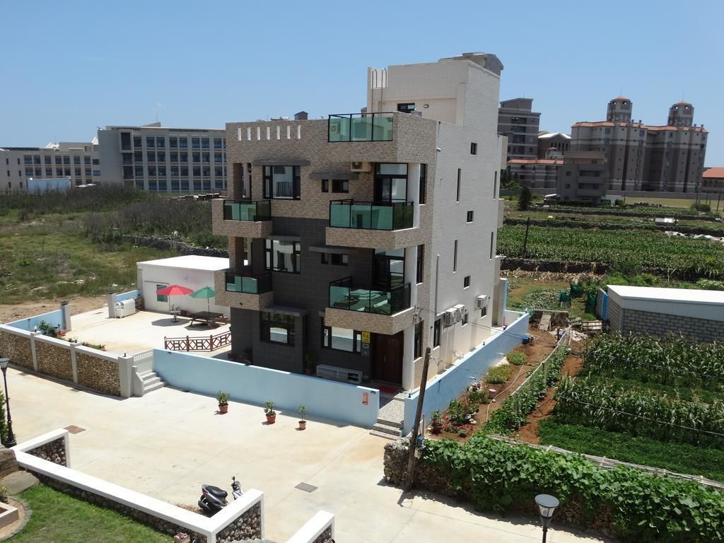 A modern multi-story building with balconies and a rooftop patio area.