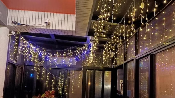 A corridor with string lights, potted plants, and a door leading to another area. - Chang Cheng Min Su (Magong)