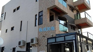 A modern building with a stone facade, multiple balconies, and a glass entrance. - Chang Cheng Min Su (Magong)