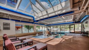 A spacious indoor pool area with a glass ceiling, multiple seating areas, and a visible waterfall feature. - Luxury|In Town|Peak 9|Ski-In/Out (Breckenridge)