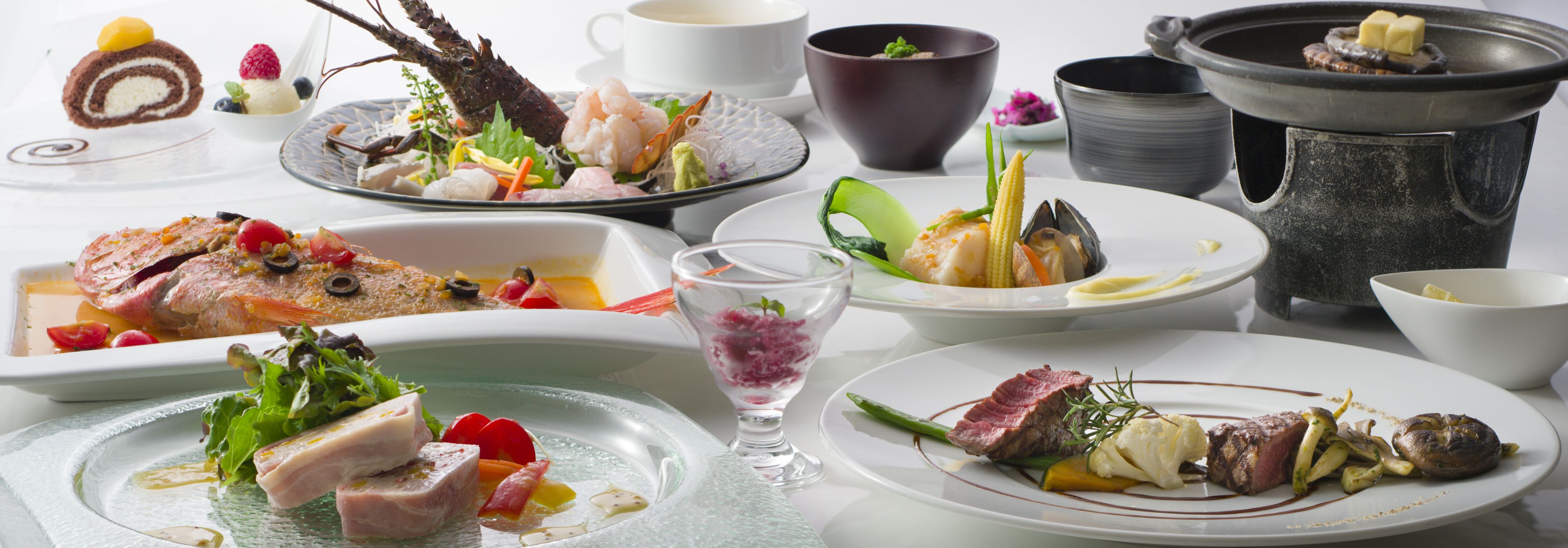 A variety of dishes on a table, including seafood, meat, and vegetables, with a teapot and cups in the background.