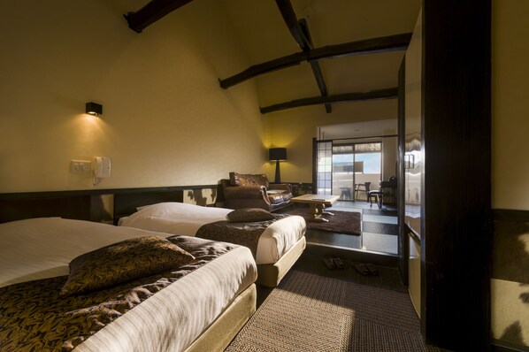 A hotel room with a large bed, a smaller sofa, and a view of the outside. - Hoozue No Toki (Izu)