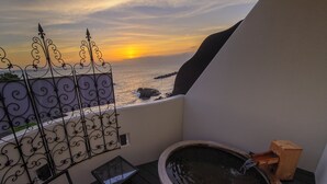 A balcony with a hot tub, a view of the sea, and a decorative metal fence. - Hoozue No Toki (Izu)