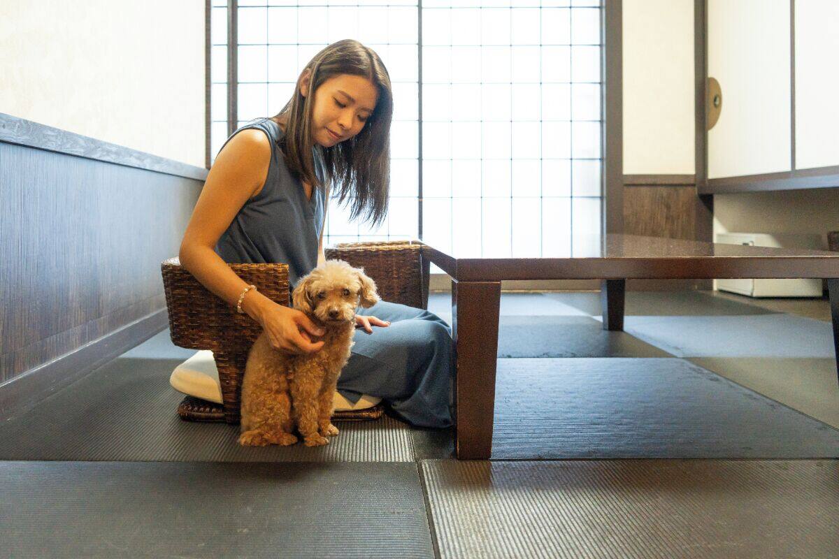A person sitting on a mat with a small dog.