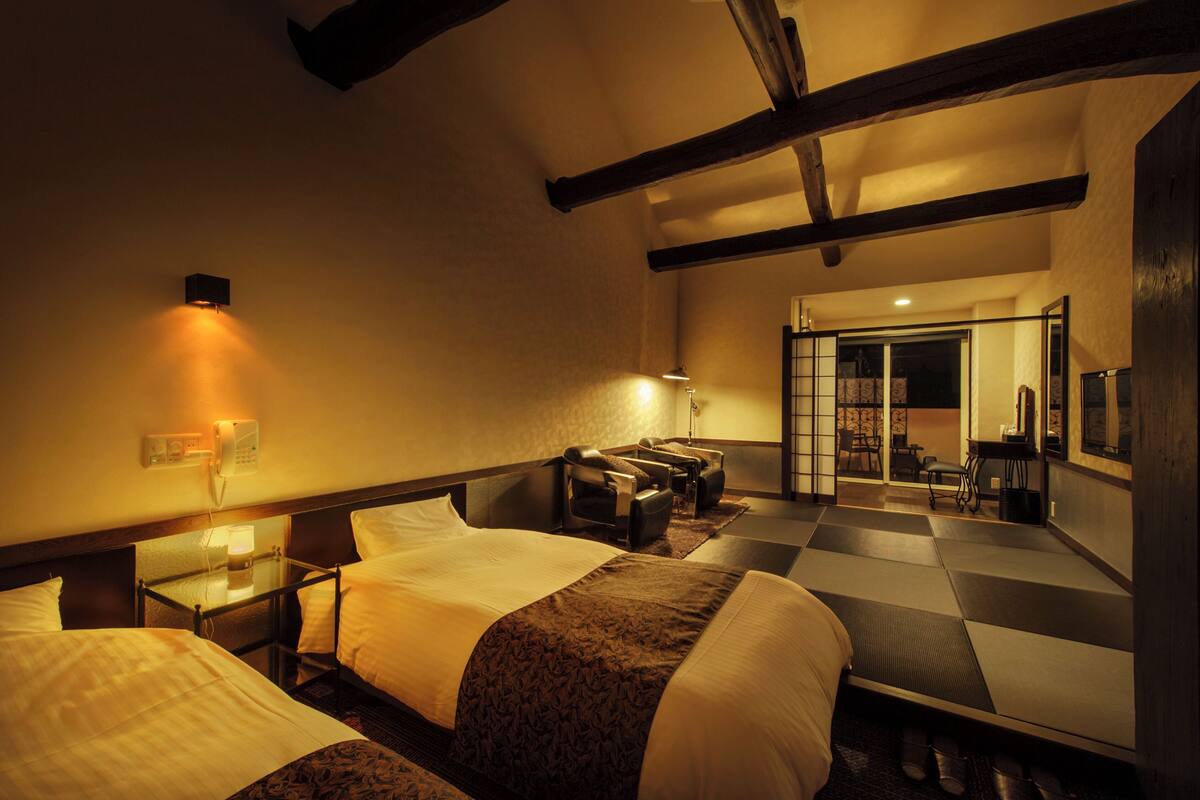 A hotel room with two beds, a massage chair, a small table, and a mirror.