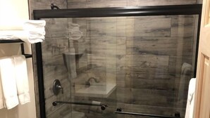 A modern bathroom with a glass-enclosed shower, a toilet, and a sink.