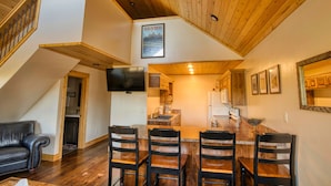 A spacious kitchen with a wooden ceiling, a dining area with a large island, and a living area with a staircase.