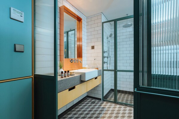 Un baño moderno con un espejo grande, un lavabo y una zona de ducha.