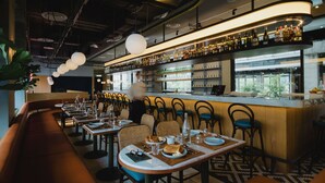 Um restaurante com área de bar, mesas montadas com pratos e copos, e vista para o exterior.