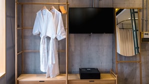 Quarto com guarda-roupa de madeira, televisão de tela plana e espelho.