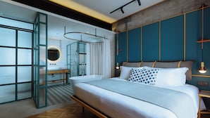 Un dormitorio moderno con una cama grande, cabina de ducha de vidrio y piso de madera.