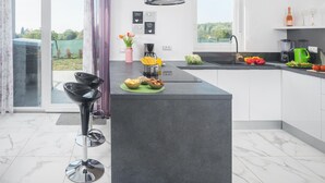 Una cocina moderna con una isla central, una cafetera y vistas al exterior.
