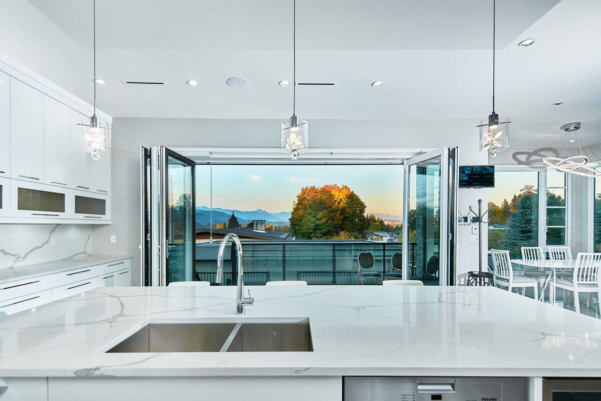 A modern kitchen with a large island, a built-in sink, and a view of the outdoors.