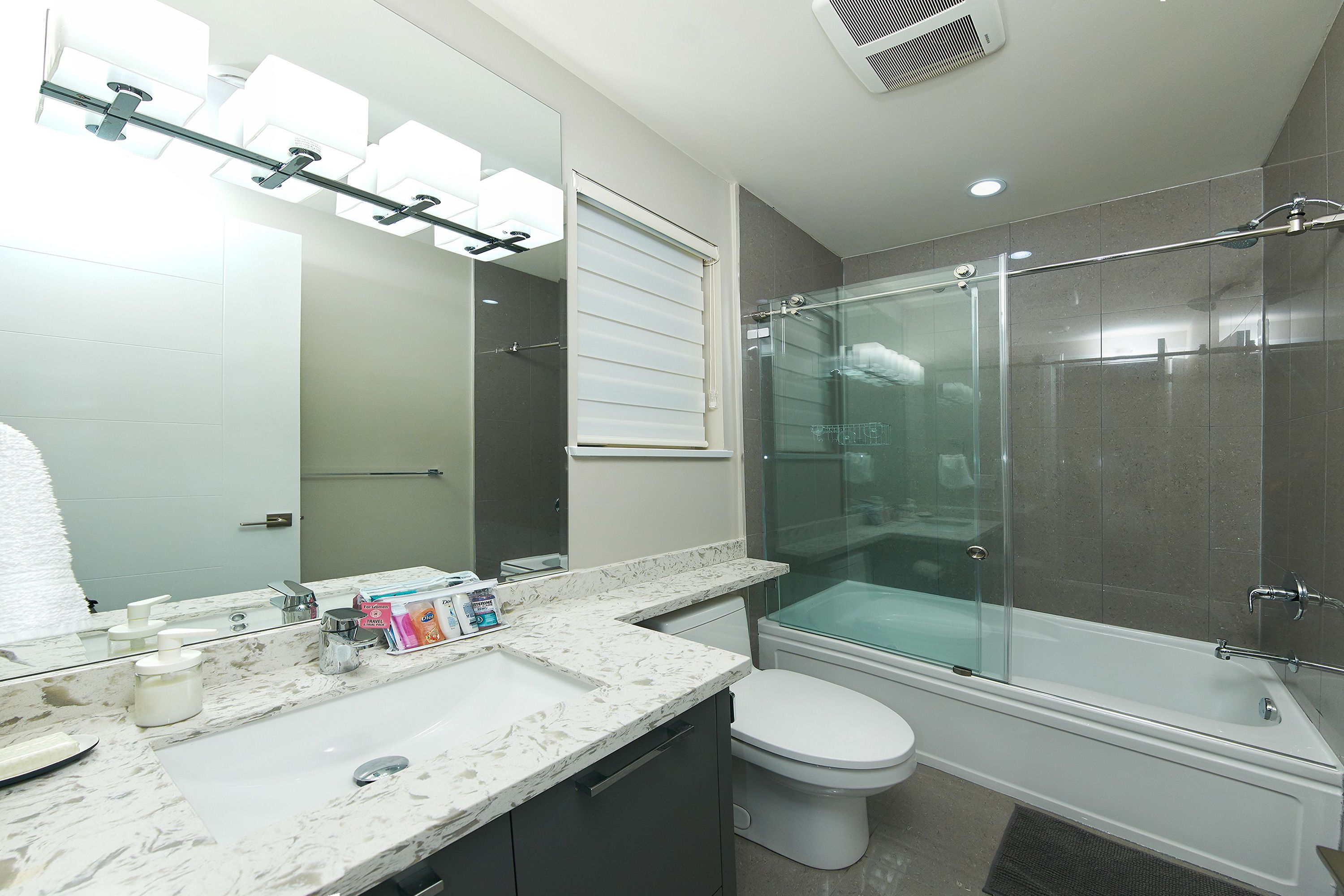 A modern bathroom with a glass-enclosed shower, a white toilet, and a marble countertop.