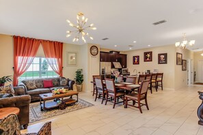 A spacious living room with a sofa, coffee table, and dining area with chairs and a table.
