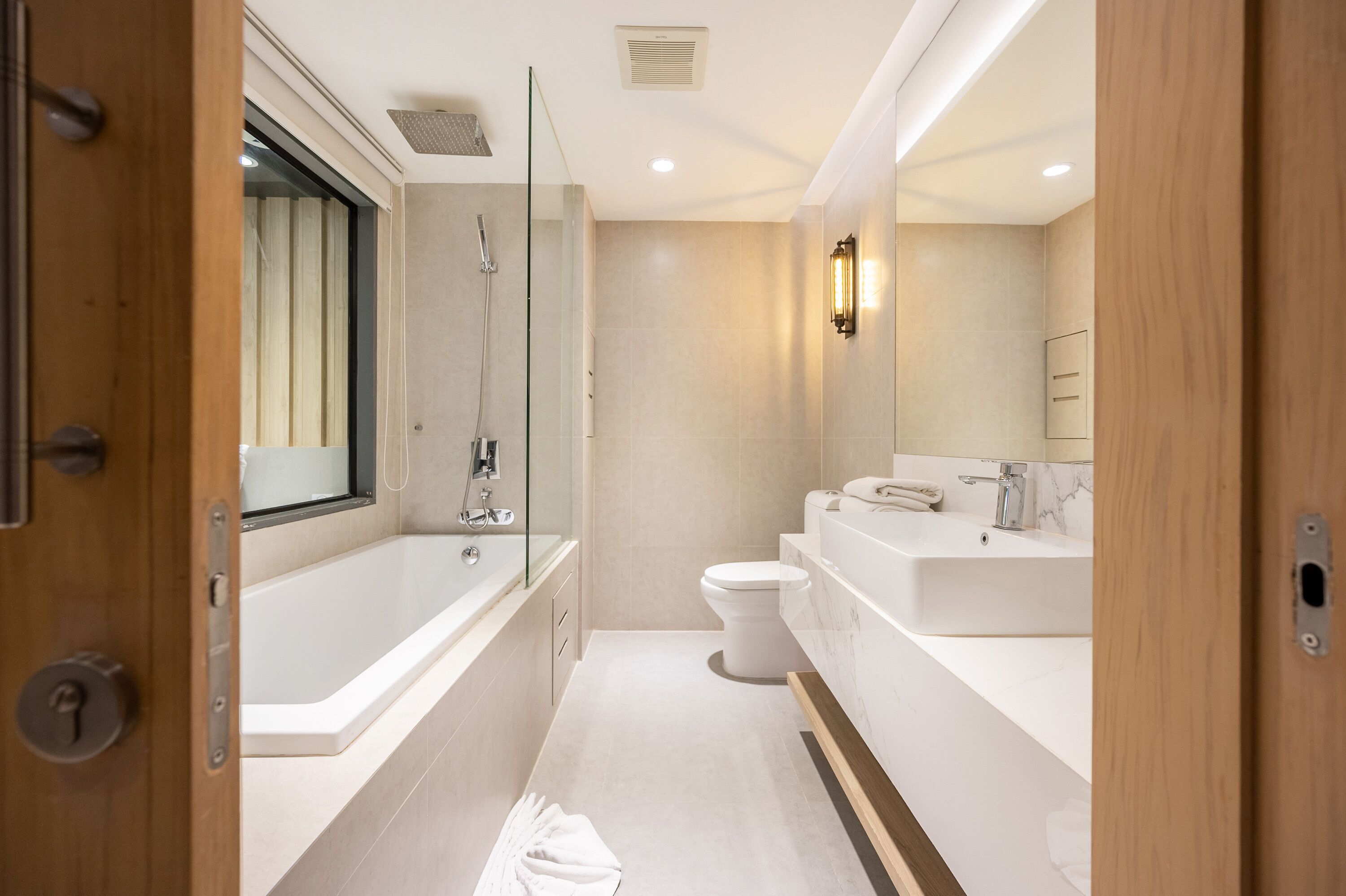 A modern bathroom with a glass shower enclosure, a bathtub, a toilet, and a vanity with a sink and mirror.
