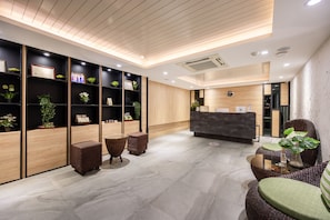 A modern reception area with a wooden reception desk, wicker furniture, and potted plants. - Loft Bangkok Hotel (Bangkok)
