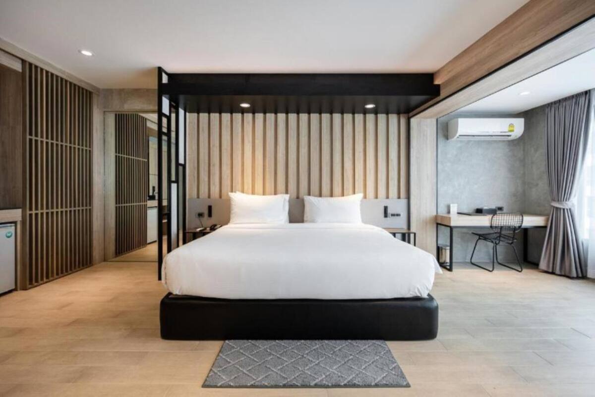 A modern bedroom with a large bed, a desk, and a chair.