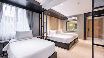 Une chambre d’hôtel moderne avec deux lits, une grande fenêtre avec des rideaux, un mur revêtu de panneaux en bois et un miroir au-dessus des lits.