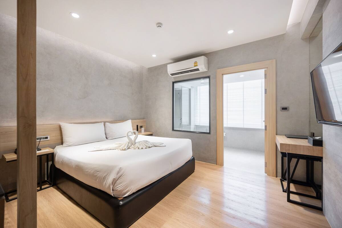 A modern hotel room with a large bed, a desk, and a TV.