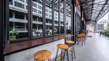 Un café moderne avec de grandes fenêtres, des tabourets en bois et un sol carrelé.