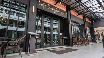 L'extérieur de l'hôtel Lotte de Bangkok se caractérise par de grandes portes vitrées, des meubles en osier disposés à l'extérieur et une architecture moderne.