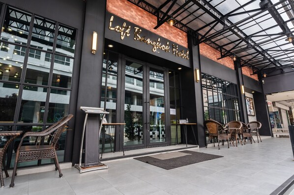 The exterior of Lotte Bangkok Hotel with large glass doors, wicker furniture outside, and a modern architectural design. - Loft Bangkok Hotel (Bangkok)