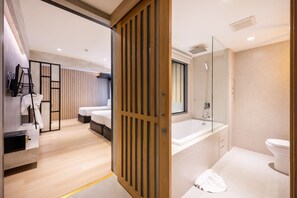 A modern hotel room with a wooden floor, a large bed, a bedside table, and a mirror. - Loft Bangkok Hotel (Bangkok)